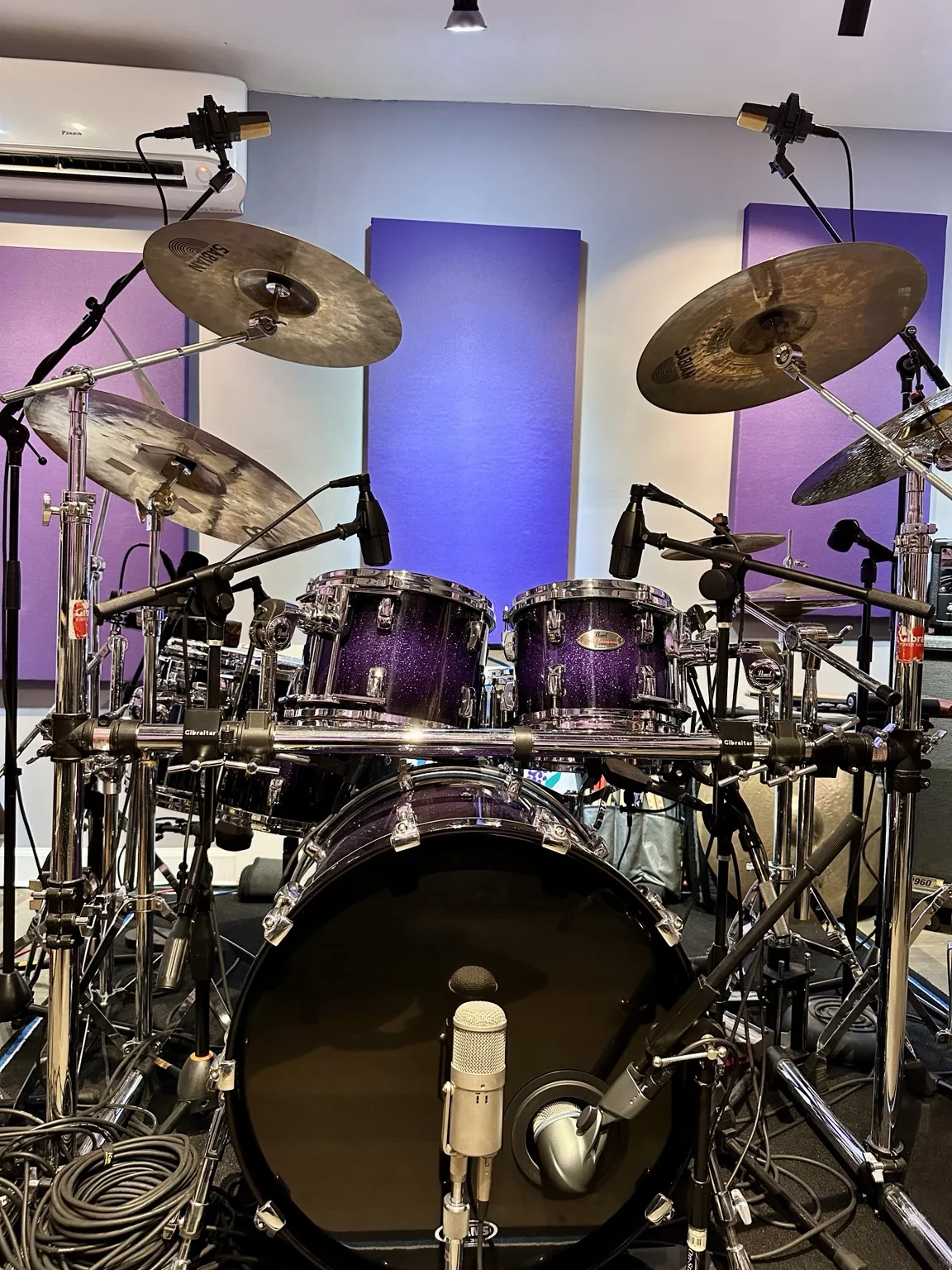 A full acoustic drum kit set up with overhead microphones