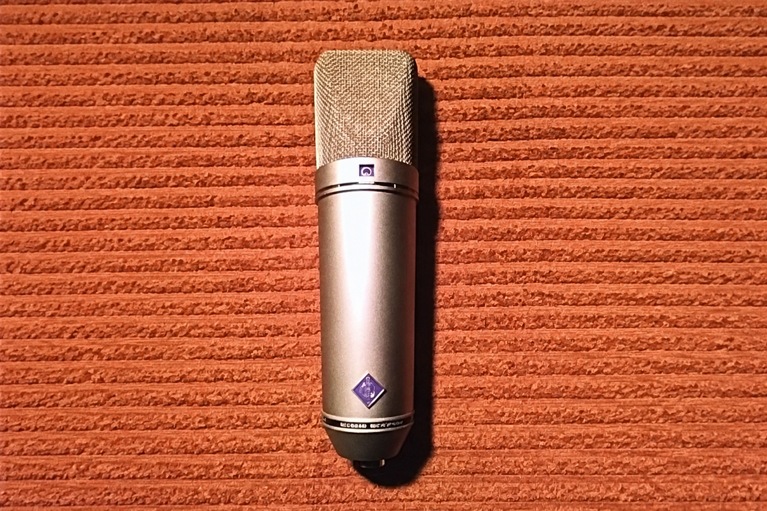A studio condenser microphone against an acoustic wall panel