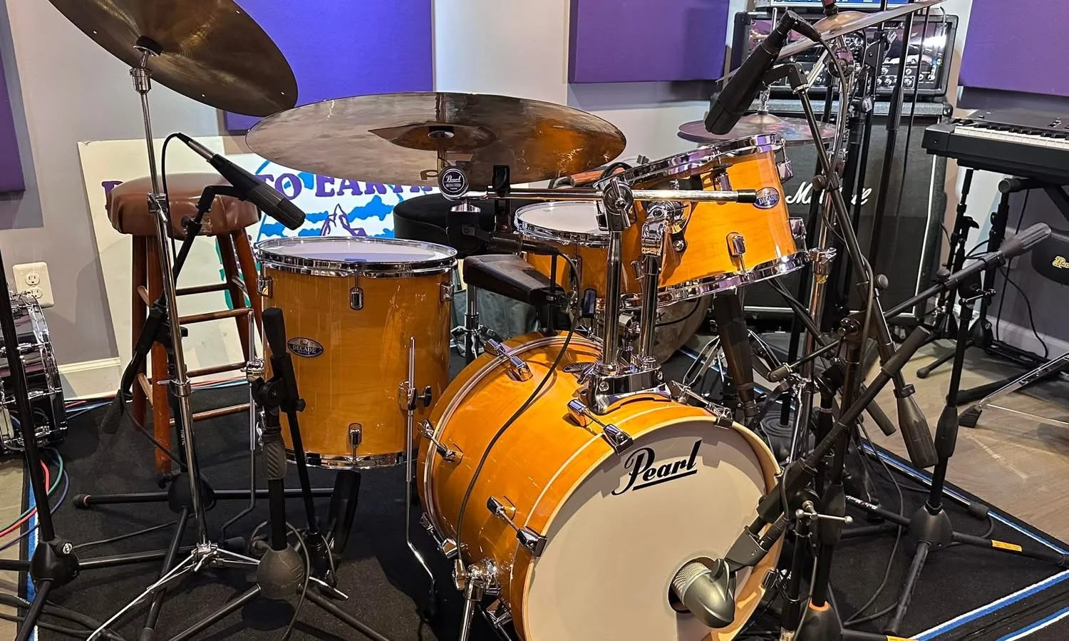 An orange acoustic drum kit with microphones in the studio